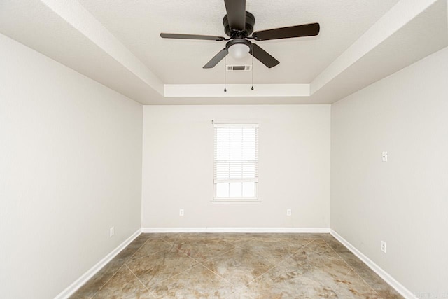 empty room featuring ceiling fan, a textured ceiling, and a tray ceiling