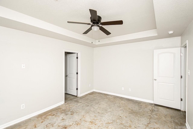 unfurnished room with a tray ceiling, ceiling fan, and a textured ceiling