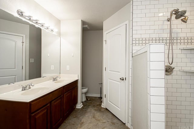 bathroom featuring a textured ceiling, a tile shower, vanity, and toilet