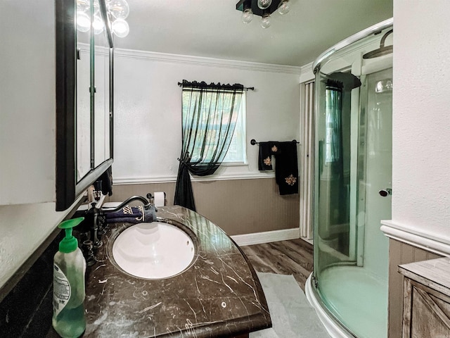 bathroom featuring vanity, hardwood / wood-style flooring, a shower with shower door, and crown molding