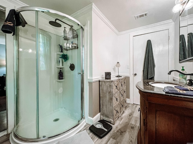 bathroom with ornamental molding, vanity, hardwood / wood-style floors, and a shower with door