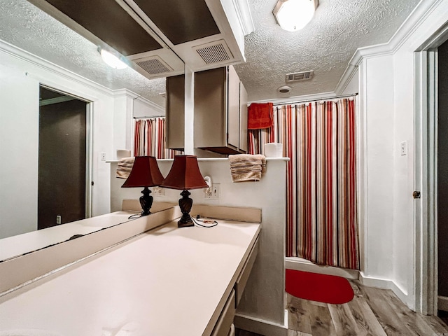 bathroom with a textured ceiling, wood-type flooring, vanity, and ornamental molding