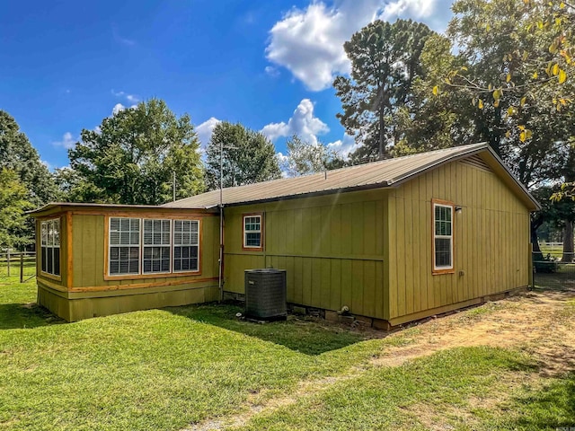 rear view of house featuring a lawn and central AC unit