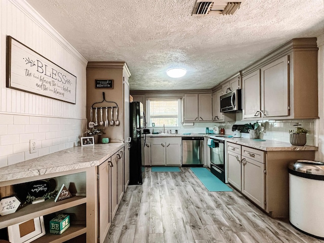 kitchen with sink, a textured ceiling, black appliances, crown molding, and light hardwood / wood-style floors