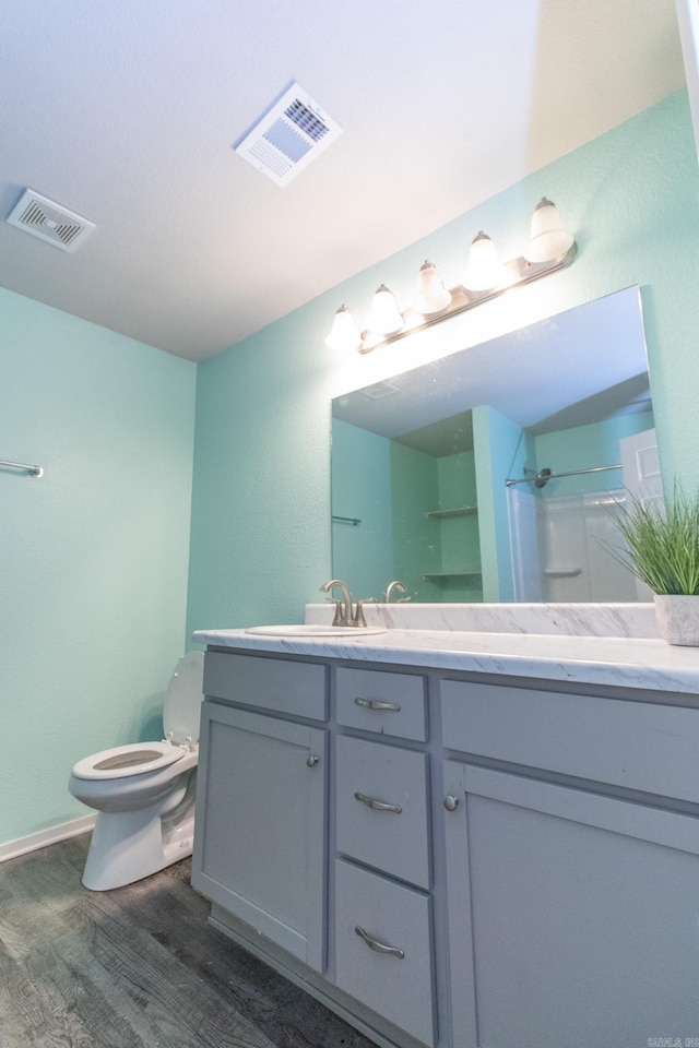 bathroom featuring a shower, vanity, toilet, and hardwood / wood-style flooring