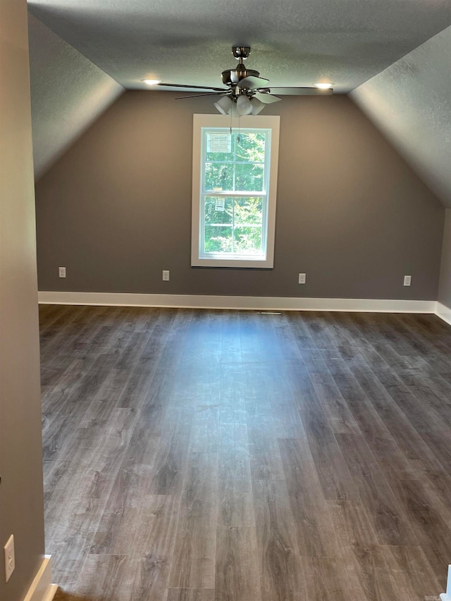 bonus room featuring vaulted ceiling, a textured ceiling, dark hardwood / wood-style floors, and ceiling fan