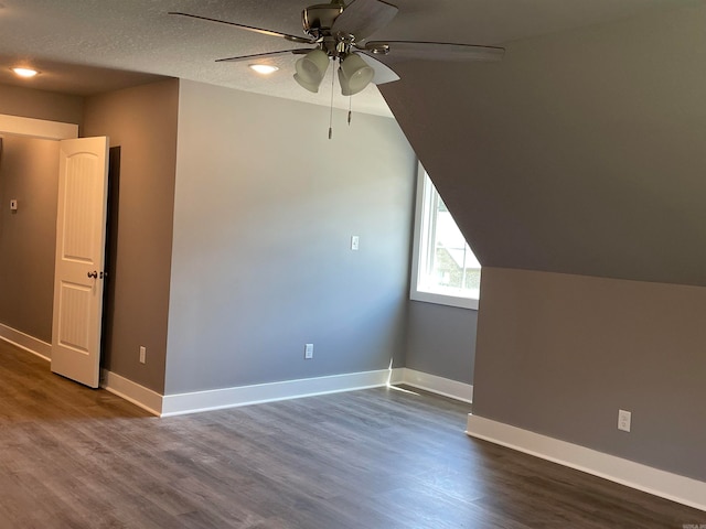 bonus room featuring lofted ceiling, ceiling fan, dark wood-type flooring, and a textured ceiling