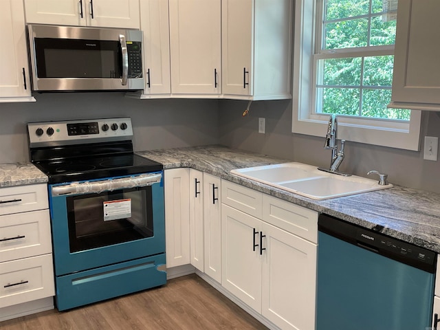 kitchen featuring stainless steel appliances, white cabinets, and plenty of natural light