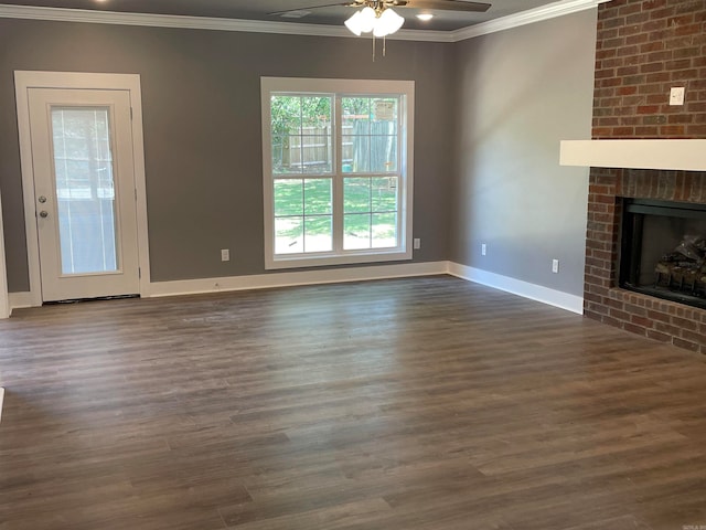 unfurnished living room featuring a brick fireplace, ceiling fan, crown molding, and dark hardwood / wood-style flooring