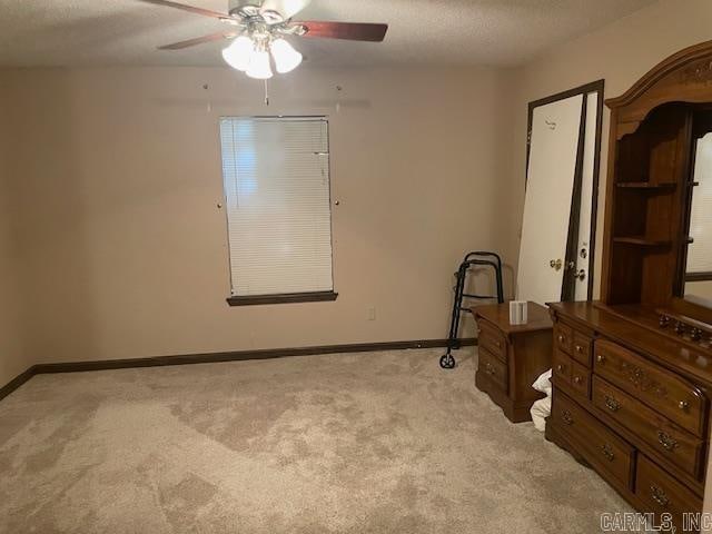 carpeted bedroom featuring ceiling fan and a textured ceiling