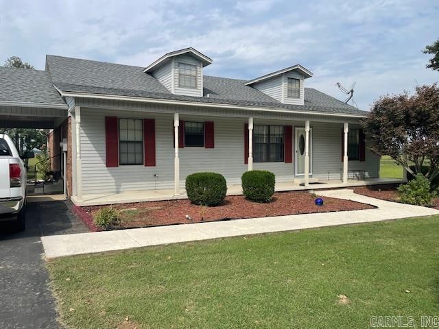 view of front of property featuring a carport, a front yard, and covered porch