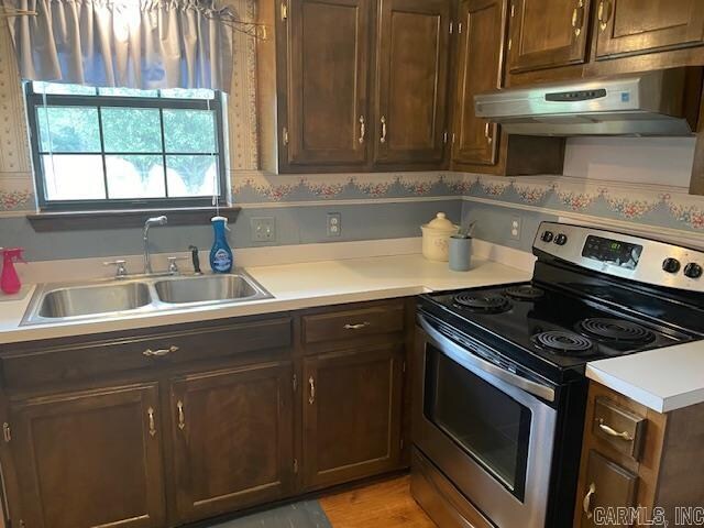 kitchen featuring stainless steel range with electric cooktop, dark brown cabinetry, and sink