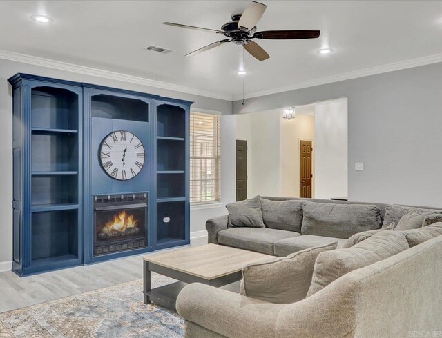 living room with ceiling fan, light hardwood / wood-style flooring, a fireplace, and ornamental molding