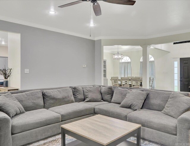 living room featuring ceiling fan with notable chandelier and crown molding