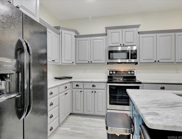 kitchen with appliances with stainless steel finishes, backsplash, gray cabinetry, and light wood-type flooring