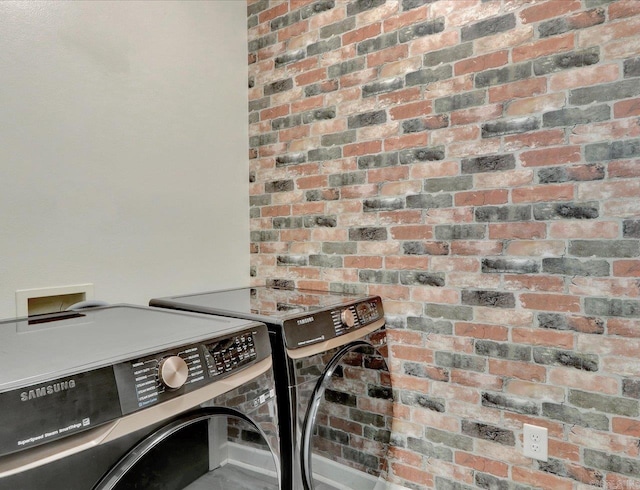 laundry room with brick wall and independent washer and dryer