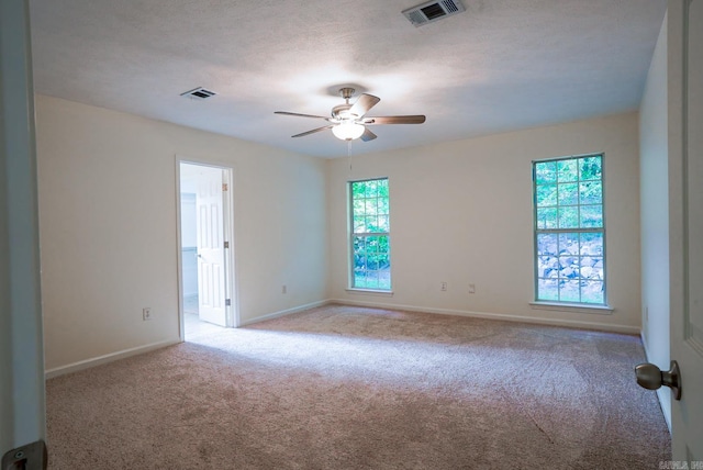 empty room featuring light carpet, a textured ceiling, and ceiling fan