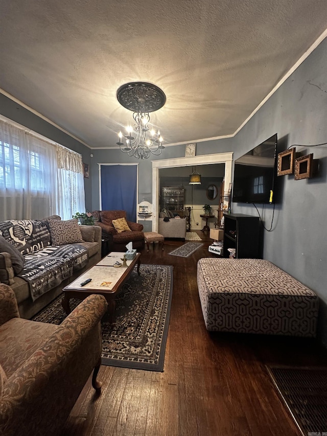 living area featuring a textured ceiling, ornamental molding, wood-type flooring, and a notable chandelier