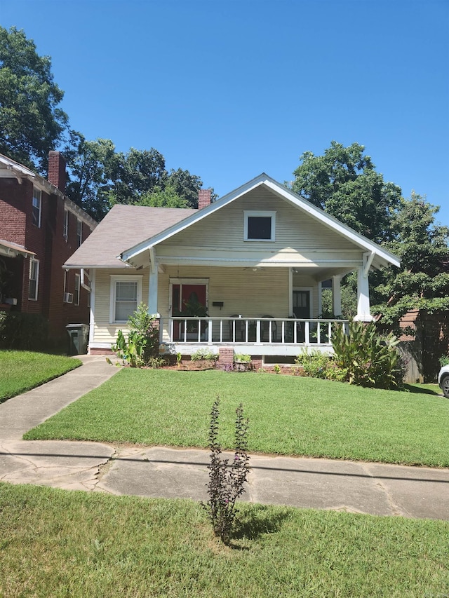 bungalow-style home with a chimney, a porch, and a front yard