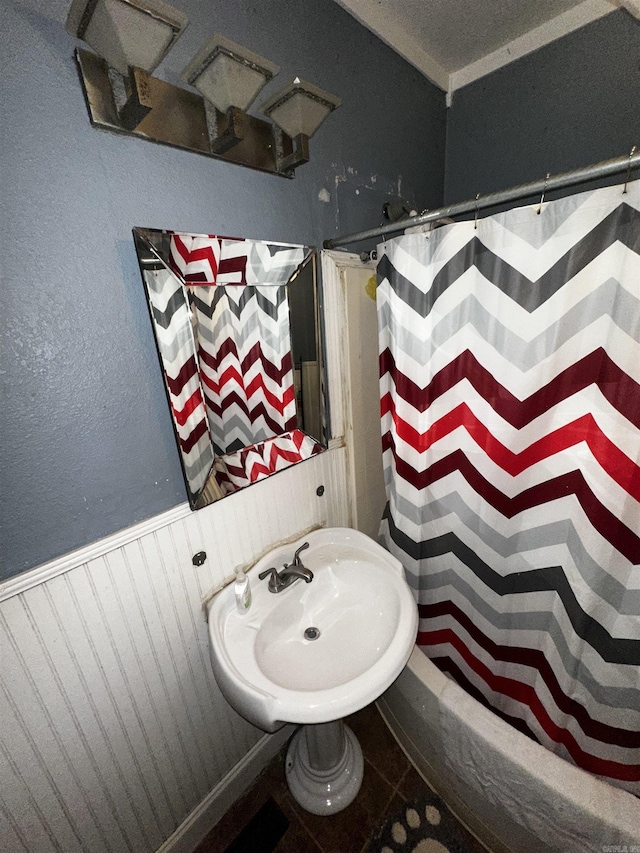 full bathroom with a wainscoted wall, a shower with curtain, and a sink