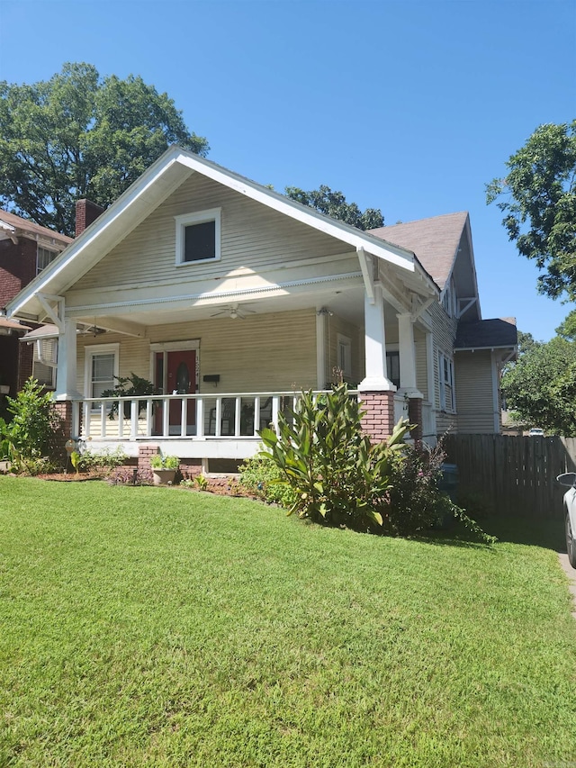 rear view of property featuring fence, a porch, and a yard