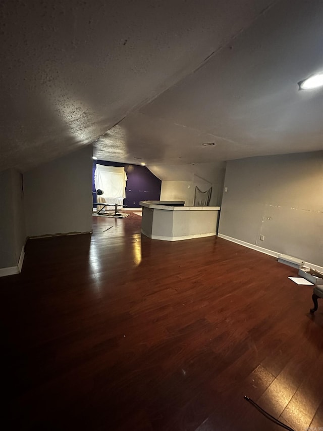 bonus room with lofted ceiling, dark wood-type flooring, and baseboards