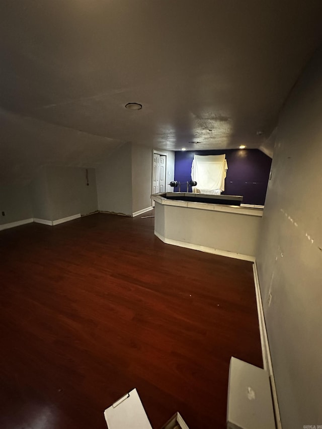 interior space with lofted ceiling, baseboards, and wood finished floors