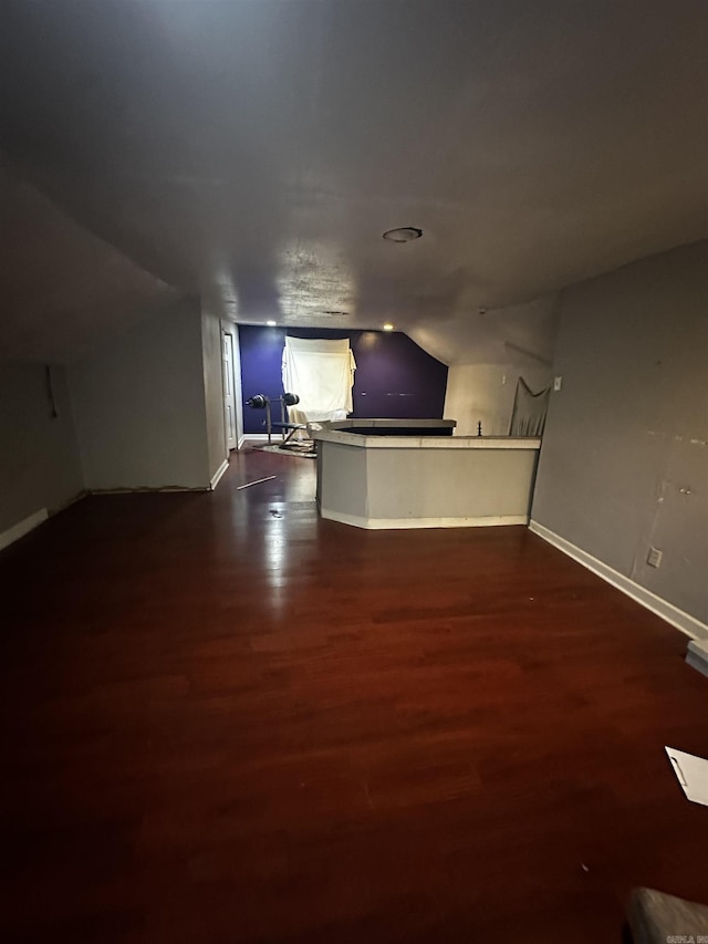 bar featuring lofted ceiling, dark wood finished floors, and baseboards