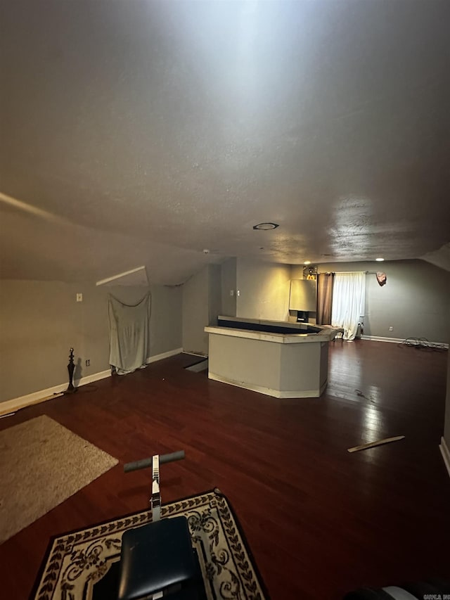 interior space featuring lofted ceiling, dark wood finished floors, and baseboards