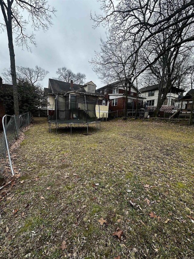 view of yard featuring a trampoline and fence