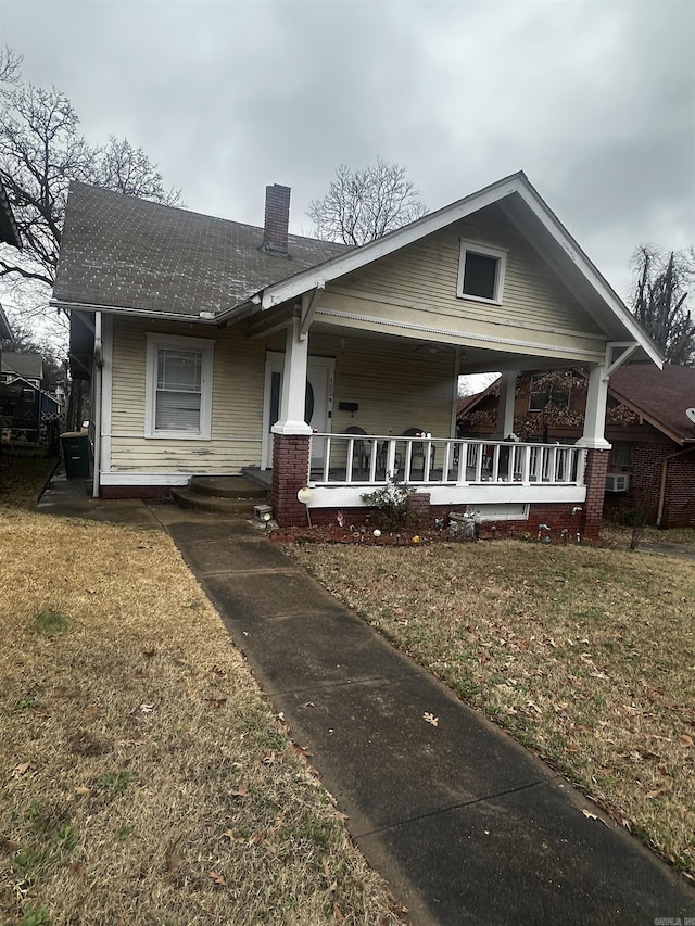 view of front of house featuring a chimney, a front lawn, and a porch