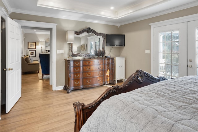 bedroom with a tray ceiling, light hardwood / wood-style floors, and crown molding