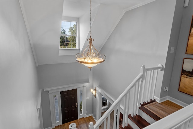 entrance foyer with hardwood / wood-style flooring, ornamental molding, vaulted ceiling, and a notable chandelier