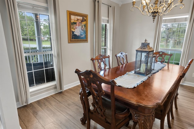 dining space with a notable chandelier, light wood-type flooring, plenty of natural light, and ornamental molding