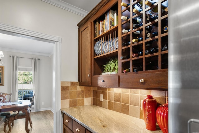 interior space featuring ornamental molding, light wood-type flooring, light stone counters, and backsplash