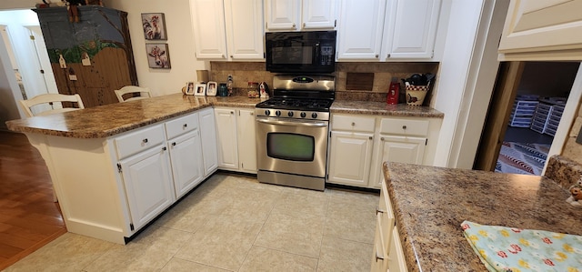 kitchen featuring stainless steel range with gas cooktop, kitchen peninsula, a breakfast bar area, and white cabinets