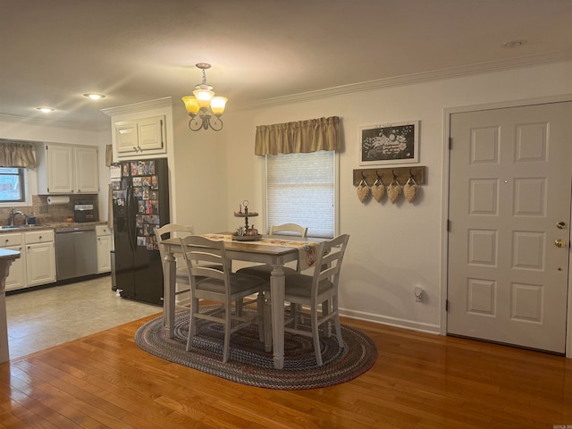 dining room featuring ornamental molding, light wood-type flooring, a chandelier, and sink