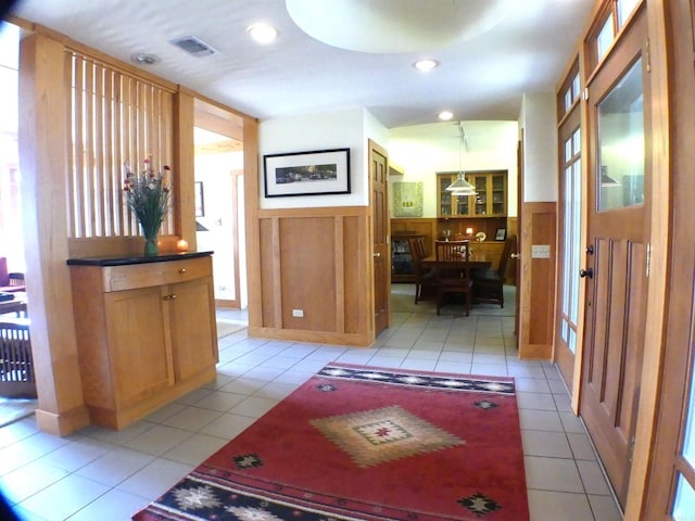 hall featuring light tile patterned floors, a wealth of natural light, and wooden walls