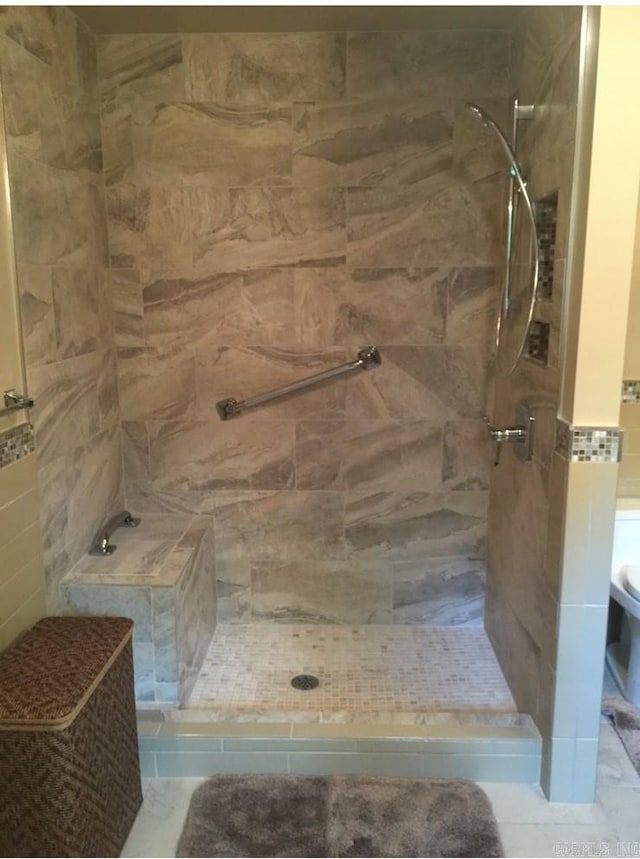 bathroom featuring a tile shower, tile walls, and toilet