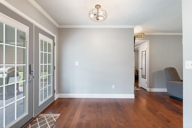 unfurnished room with french doors, ornamental molding, an inviting chandelier, and dark wood-type flooring