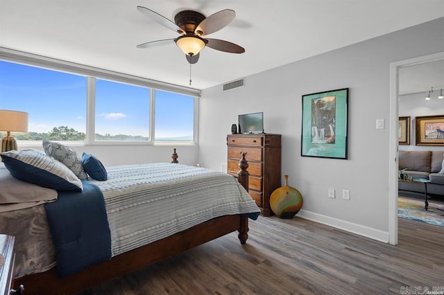 bedroom with dark hardwood / wood-style flooring, ceiling fan, and track lighting