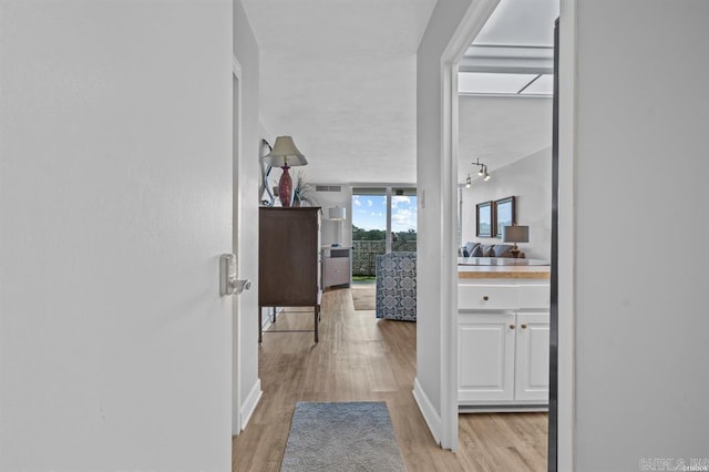 corridor featuring light wood-style flooring and baseboards