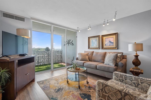 living room with floor to ceiling windows, rail lighting, and hardwood / wood-style floors