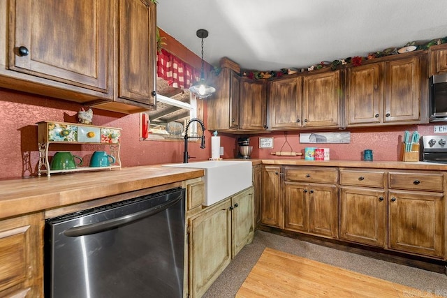 kitchen featuring wood counters, stainless steel appliances, hanging light fixtures, and sink