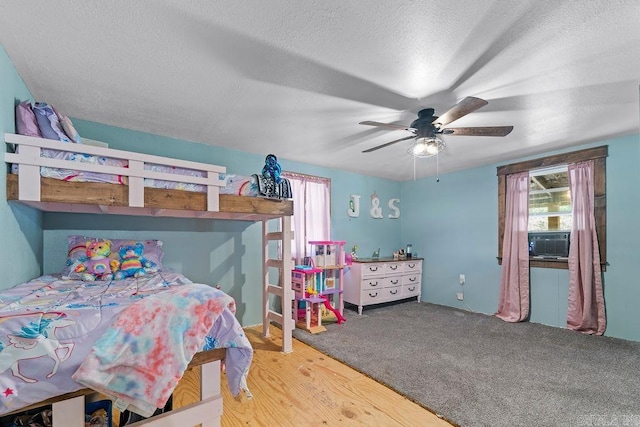 carpeted bedroom with a textured ceiling, ceiling fan, and cooling unit