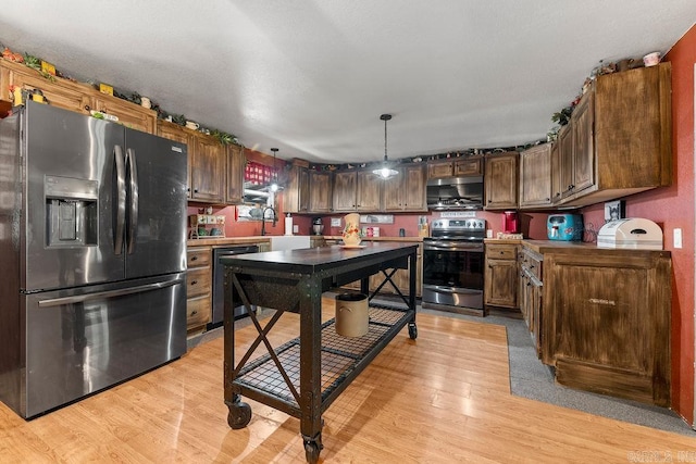 kitchen with decorative light fixtures, stainless steel appliances, light hardwood / wood-style flooring, and dark brown cabinets