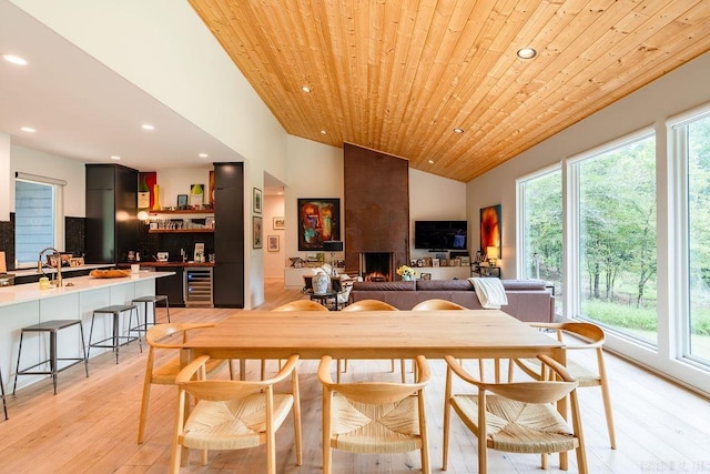 dining space with wine cooler, wood ceiling, sink, light hardwood / wood-style flooring, and vaulted ceiling