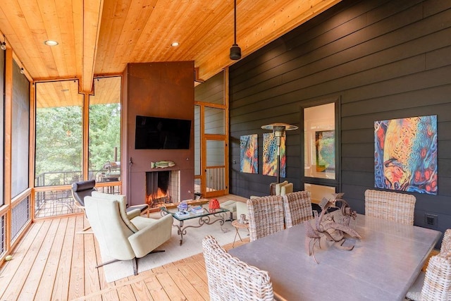 dining area featuring wood ceiling, a fireplace, wood walls, lofted ceiling, and light hardwood / wood-style flooring