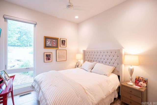 bedroom with ceiling fan, wood-type flooring, and multiple windows