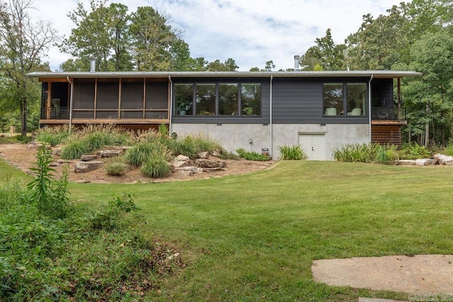 rear view of house featuring a sunroom and a lawn